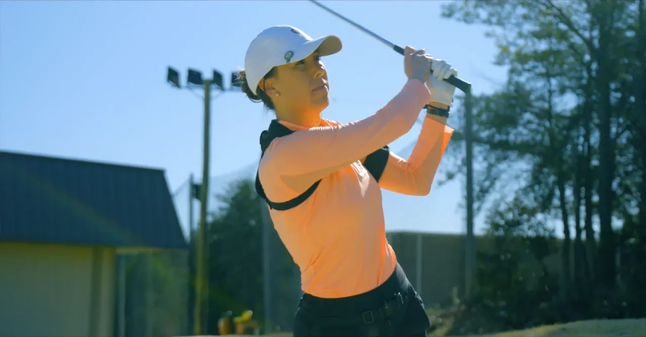 Golfer at the top of the follow-through on a sunny range