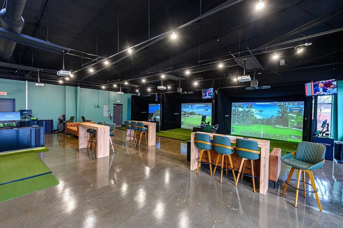 Interior of the 019 GolfHouse indoor golf studio in Greer, SC — simulator bays, seating, and putting turf