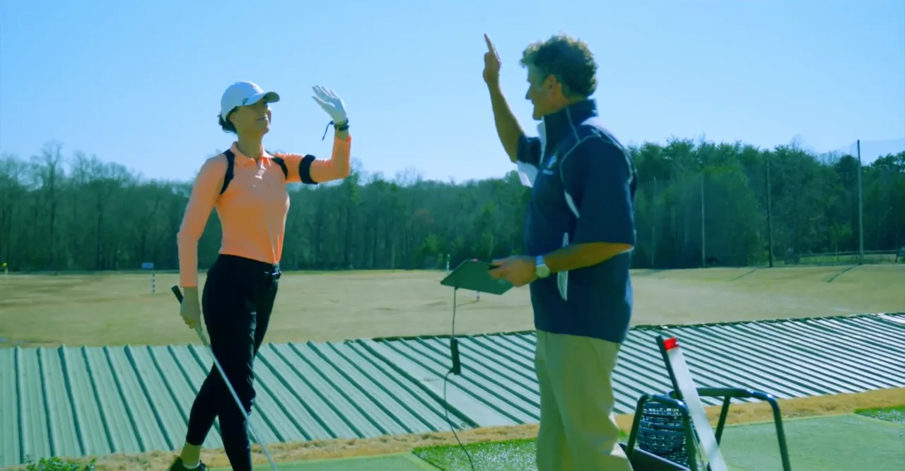 Bo coaching a student on the outdoor range at Haas Family Golf in Greenville